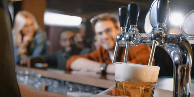 Beer being poured at a bar with patrons in the background - Florida dram shop liability